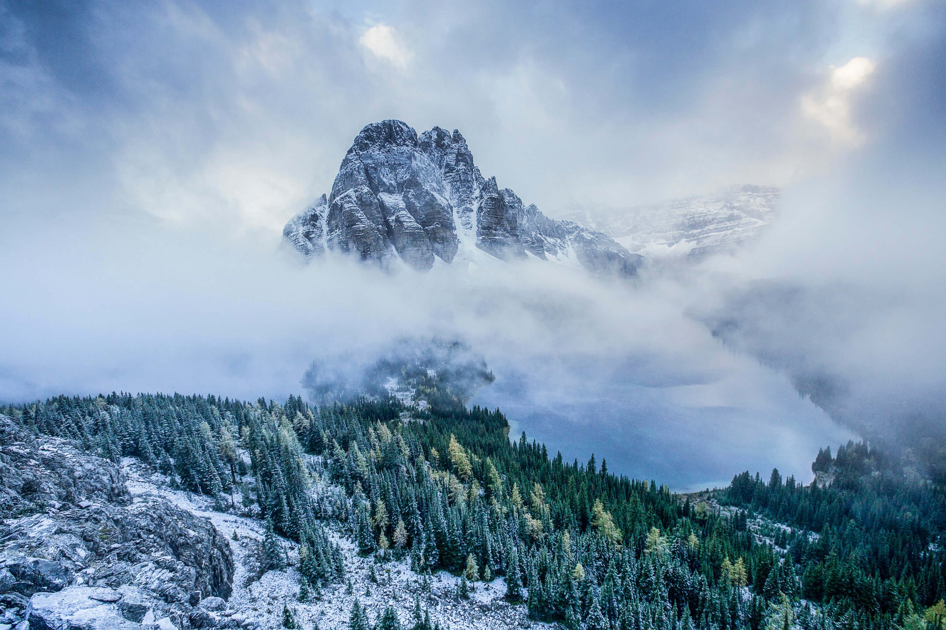 First snow atop Sunburst Peak of Mt Assiniboine in Canada with clouds rolling through the valley